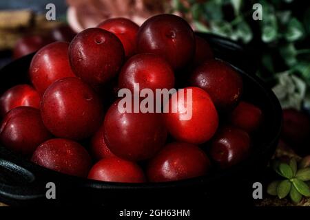 Bowl with fresh sweet plums served on black table Stock Photo