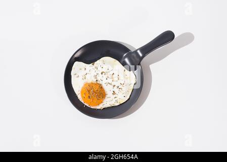 Delicious fried egg on black skillet served on table on white background in studio Stock Photo