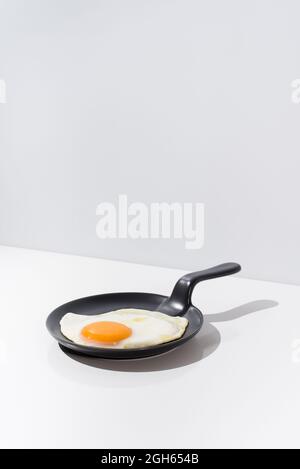Delicious fried egg on black skillet served on table on white background in studio Stock Photo