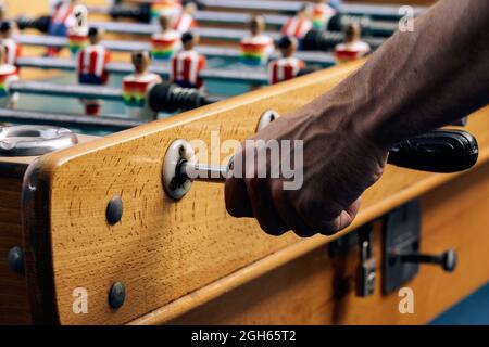 Crop unrecognizable African American male playing table soccer game while entertaining at weekend Stock Photo