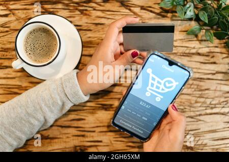 From above of crop unrecognizable female with plastic card making purchase for order and using mobile application for online shopping on smartphone wh Stock Photo