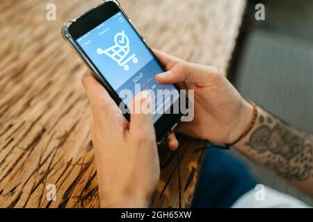 Crop anonymous male using application for online shopping on mobile phone and making payment for order Stock Photo