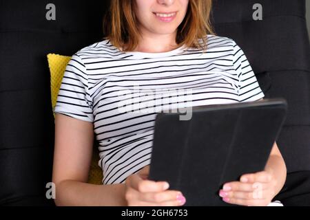 Woman using tablet for video conversation while relaxing on couch. Young man working at home Stock Photo