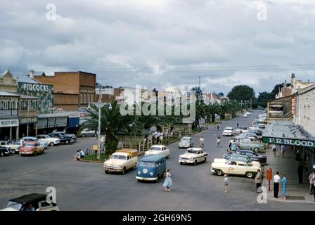 Grafton, NSW, Australia in 1959 – this view is looking north up Prince Street from the junction with Fitzroy Street. Although there are plenty of cars, there are also many people on bicycles. The wide central reservation (median strip) has shelters for bikes – it also seems to be a meeting place, with people gathered in the middle of the road under the large fan palm trees! Grafton is a city in the Northern Rivers region in the state of New South Wales, located on the Clarence River. This image is from an old amateur Kodak colour transparency – a vintage 1950s photograph. Stock Photo