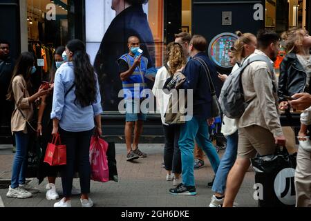London (UK), 28 August 2021: An NHS support worker hands out frre rapid covid test kits to members of the public on Carnaby Street in London. Stock Photo