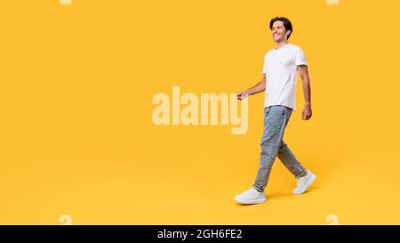 Young bearded man walking isolated on yellow background Stock Photo