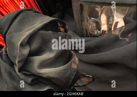 Underworld scene. Grim reaper warns of death and fire. Soft sculpture art in foreground as a demon, witch, devil figure by lantern and orange fire. Stock Photo