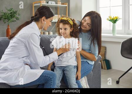 Family doctor or pediatrician listening to little girl's breath or heartbeat during home visit Stock Photo