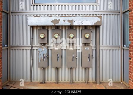 CHARLOTTE, NC, USA-25 JULY 2021: A wall of four electric power meters and boxes of breakers along with a master on/off switch. Stock Photo
