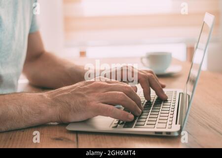 Working from home, male hands typing laptop computer keyboard, closeup with selective focus Stock Photo