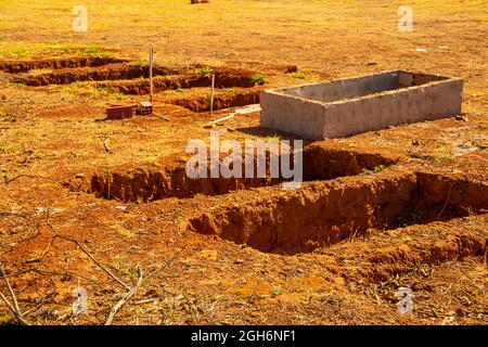 Details of open graves in a cemetery. Holes drilled in the ground for graves. Stock Photo
