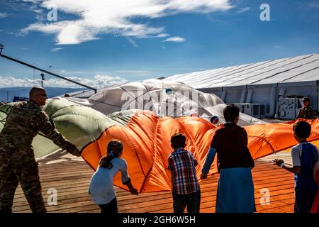 U.S. Air Force airmen play the parachute game with young Afghan refugees evacuated from Kabul during their stay at Holloman Air Force Base September 3, 2021 in Alamogordo, New Mexico. Holloman has created temporary housing for at least 50,000 Afghan evacuees. Stock Photo