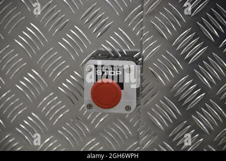 An Emergency stop red button installed on metal wall Stock Photo