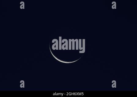 Waning crescent on the dark morning sky Stock Photo