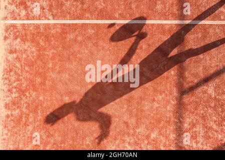 Shadow of a paddle tennis player with a racket in hand hitting the ball on an outdoor court. Stock Photo