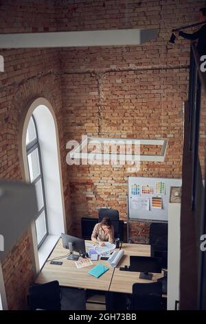 High angle view of tired woman with headache working on new project, using pc in modern office Stock Photo