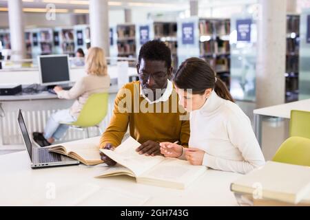 Adult female and male students working in library Stock Photo