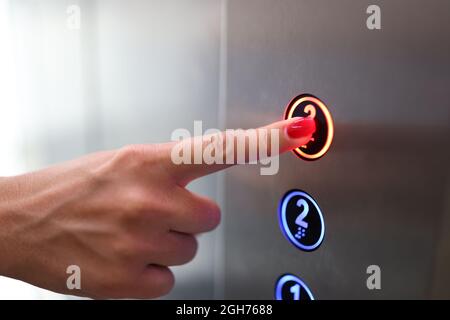 Woman finger presses a button in elevator closeup Stock Photo