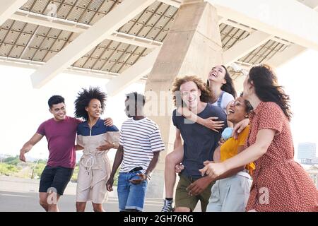 Group of friendly multi-ethnic friends having fun. Young students hugging outside the university or city. Stock Photo