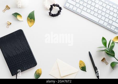Female workspace with computer keyboard, fall leaves, accessories, diary on white background. Flat lay home office desk. Top view feminine background. Stock Photo