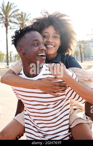 Vertical portrait of a young African-American couple in love. The girlfriend piggybacking the boyfriend. Stock Photo