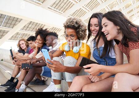 Group of young mixed race people with mobile phones. Excited students using their technological devices. Concept of young enterprising, friendly Stock Photo