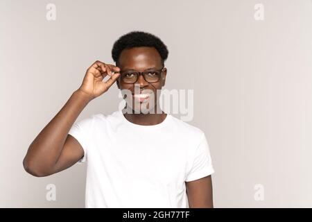 Young african guy with perfect toothy smile touch glasses wearing white t-shirt. Dentistry concept Stock Photo
