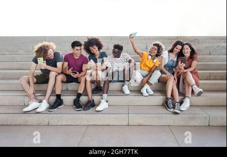 Portrait with copy space of group of mixed race people with smart phones. Excited students using their technological devices. Concept of young Stock Photo