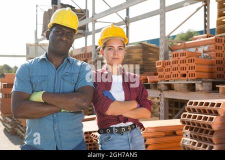 Workers in hardhats standing in construction material storage Stock Photo