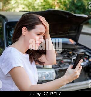 Scared woman in stress holding her head after auto crash calling to auto insurance for help. Driver woman portrait in front of wrecked car in car Stock Photo