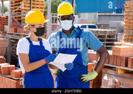 Two workers in masks keep track of the number of redbricks Stock Photo