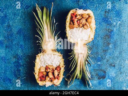 Fried chicken with rice in half of pineapple on the rustic background. Selective focus. Shallow depth of field. Stock Photo