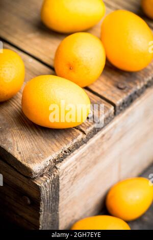 Fresh ripe kumquats on the rustic wooden background. Selective focus. Shallow depth of field. Stock Photo