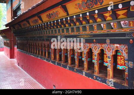 Colorful prayer wheels line a wall at the Thangtong Dewachen Dupthop Nunnery, Thimphu, Bhutan. Each spin of the wheel sends another prayer heavenward. Stock Photo