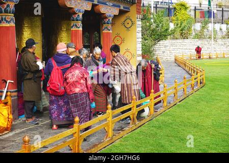 Elderly Bhutanese gather on the grounds of the National Memorial Chorten (Stupa) in Thimphu, Bhutan. Volunteers serve tea to the senior visitors. Stock Photo