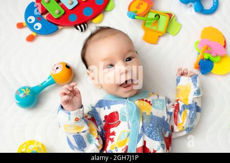 joyful baby lying on his back among toys Stock Photo