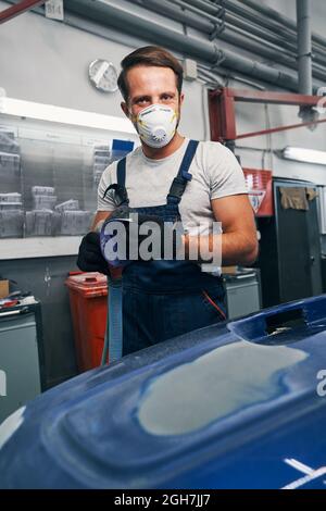 Glad automotive technician removing sandpaper from grinder Stock Photo