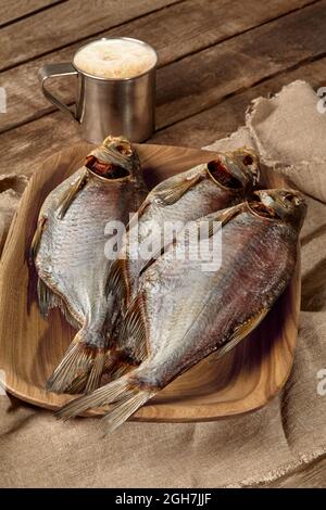 Salted sun-dried breams on wooden plate with beer in metal mug Stock Photo