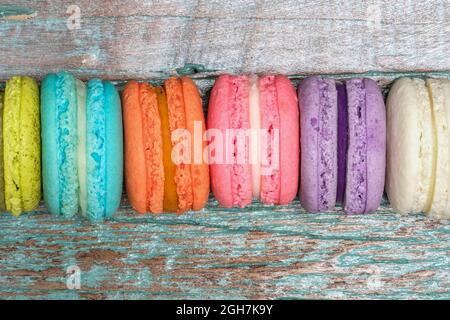 colorful macaroons on a blue-green painted wooden background, top view, isolated Stock Photo