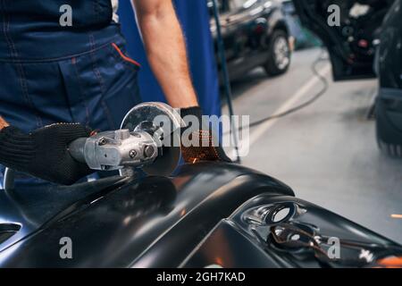 Repairmen cutting metal of car spare part with angle grinder Stock Photo