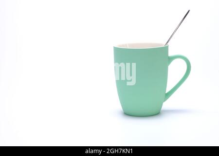 green coffee mug with spoon isolated on white background Stock Photo