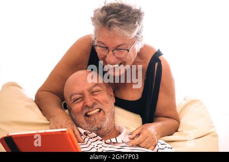 Senior couple using a digital and laughing out loud, with a white background Stock Photo