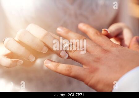 Bride and groom hands together and bride put wedding ring to grooms hand as a symbol of bonding. High quality photo Stock Photo