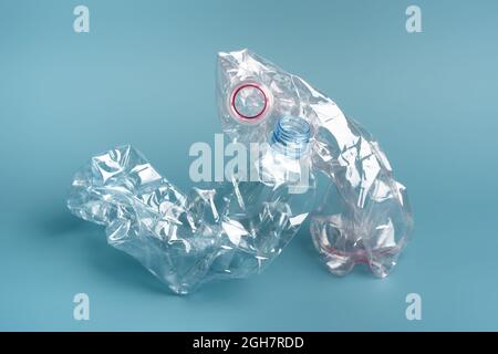 Composition of two used crushed plastic bottles on the blue background. Recycling concept. Stock Photo