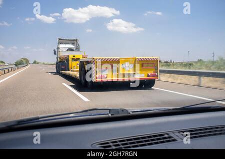 Driving behind empty oversize load truck. View from the inside of the car Stock Photo