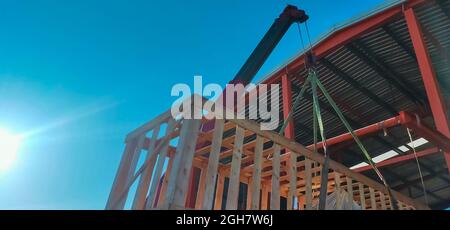 Boom truck crane lifting the machinery which storage in wooden box to stored in warehouse. Machinery transport and delivery business. Boom truck crane Stock Photo
