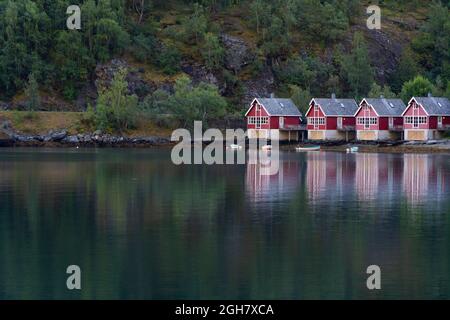 Row of four traditional red wood houses by the fjord water in Flam, Norway, Europe Stock Photo