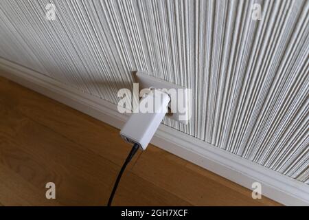 White USB phone charger plugged into a power outlet Stock Photo