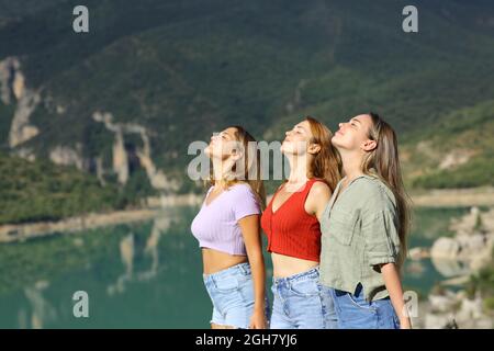 Side view portrait of three friends breathing fresh air in the mountain Stock Photo