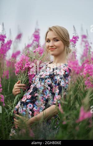 Pregnant woman at 9 months of pregnancy walks in summer in field in village, few days before the birth of the child Stock Photo